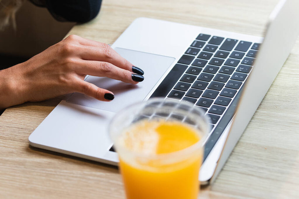 Close up of businesswoman hands typing on computer keyboard with orange juice on table. Online learning, internet marketing and freelance work concept - Zdjęcie, obraz