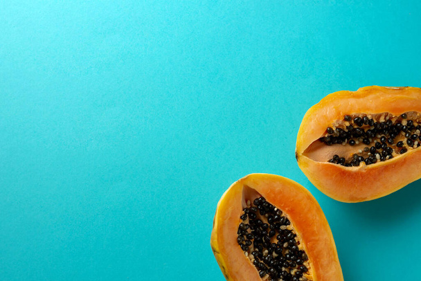 Sommerkomposition. Tropische Papayafrüchte in zwei Hälften geschnitten liegen auf blauem Hintergrund. Sommerkonzept. Flache Lage, Draufsicht, Kopierraum. - Foto, Bild