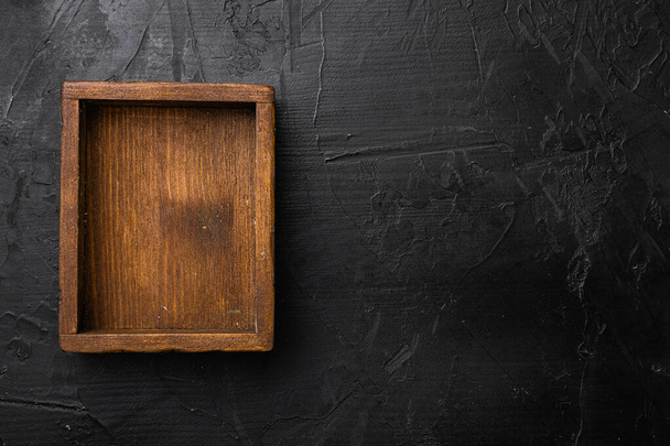 Leere dunkle Holzkiste mit Kopierraum für Text oder Lebensmittel, von oben flach liegend, auf schwarzem dunklem Steintischhintergrund - Foto, Bild