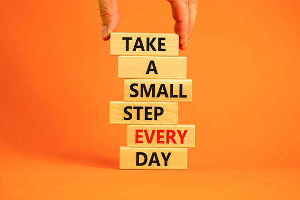 Take a small step every day symbol. Wooden blocks with words Take a small step every day. Beautiful orange background, copy space. Businessman hand. Business, step every day concept. - Fotoğraf, Görsel