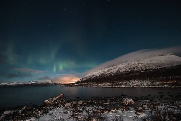 Borealis aurora sweeps over a large lake on a cloudless night in Kilpisjarvi, Lapland, Finland. aurora polaris in green dances across the sky. Scandinavian magic. Saana mountain in fog. - Photo, Image
