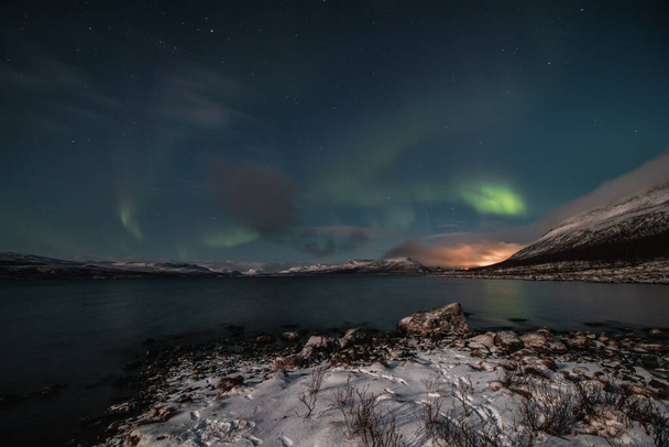 Borealis aurora veegt over een groot meer op een wolkenloze nacht in Kilpisjarvi, Lapland, Finland. aurora polaris in groene dansen door de lucht. Scandinavische magie. Saana berg in mist. - Foto, afbeelding
