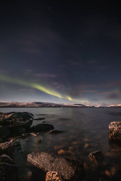 Borealis aurora barre un gran lago en una noche sin nubes en Kilpisjarvi, Laponia, Finlandia. aurora polaris en danzas verdes a través del cielo. Magia escandinava. - Foto, imagen