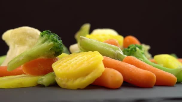 Frisches Tiefkühlgemüse auf schwarzem Hintergrund, gesunde Kost oder Diätkost für Vegetarier und Veganer, gefrorener Blumenkohl, Brokkoli und Babykarotten - Filmmaterial, Video