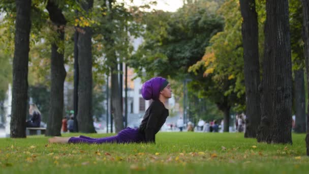 Muszlim sportos nő gyakorlat jóga nap szalutáció parkban fű reggeli rutin felfelé néző kutya pózol ászana testápolás egészséges gerinc nyújtás rugalmasság. Lány hidzsáb produktív gyakorlása - Felvétel, videó