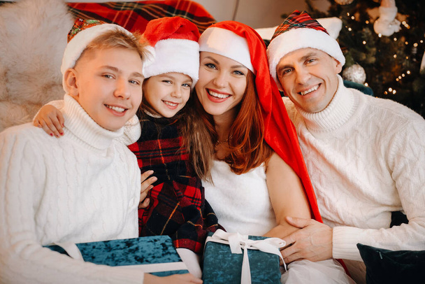Close-up portrait of a happy family sitting on a sofa near a Christmas tree celebrating a holiday. - Zdjęcie, obraz