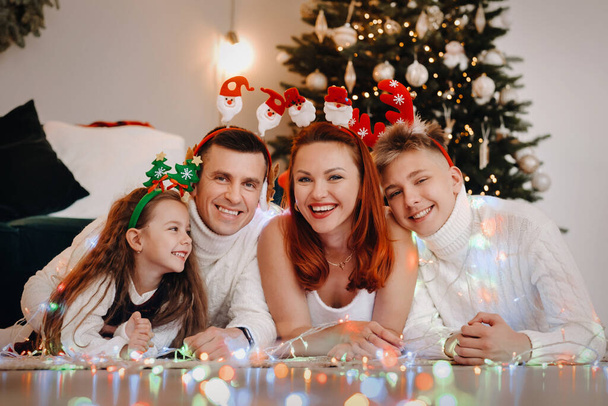 Close-up portrait of a happy family lying near a Christmas tree celebrating a holiday. - Fotoğraf, Görsel