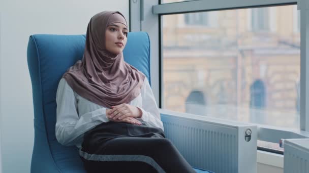 Arabialainen naispuolinen harjoittelija hijabissa odottamassa tenttiä tai haastattelun tuloksia nojatuolissa. Työehdokas istuu rekrytointiasiamiehen toimistossa ja odottaa tapaamista työnantajan kanssa. HR, urakonsepti - Materiaali, video