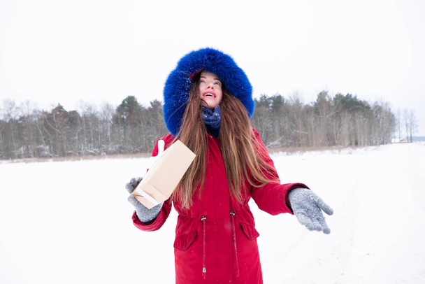Young woman in red coat enjoying snowfall  - Фото, изображение
