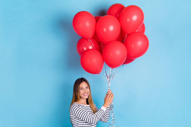 Photo of mature brown hairdo cute lady hold balloons wear white shirt isolated on blue color background - Foto, immagini