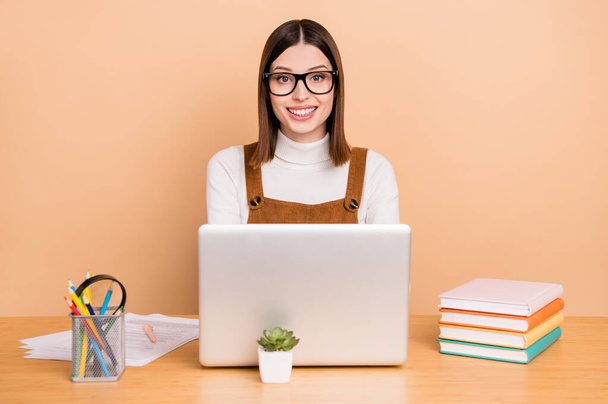 Portrait of attractive skilled cheery girl employee using laptop web programming isolated over beige color background - Zdjęcie, obraz