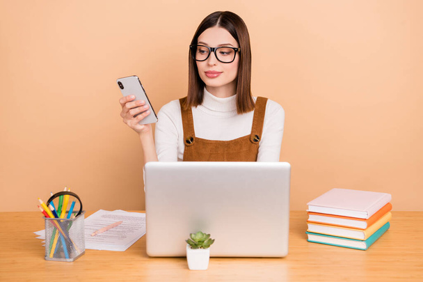 Portrait of attractive focused trendy girl employee using device consulting networking coworking isolated over beige color background - Foto, Imagen