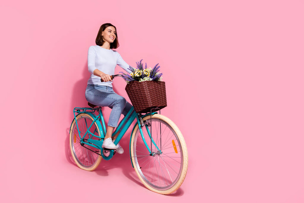 Photo of dreamy charming young woman wear white sweater driving bike looking empty space smiling isolated pink color background - Фото, зображення