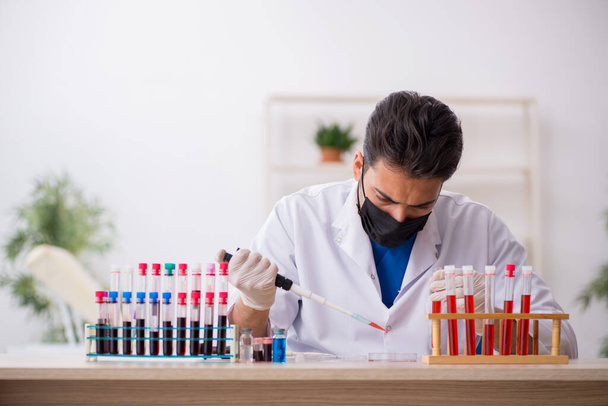 Jeune biochimiste masculin testant des échantillons de sang dans le concept de pandémie - Photo, image