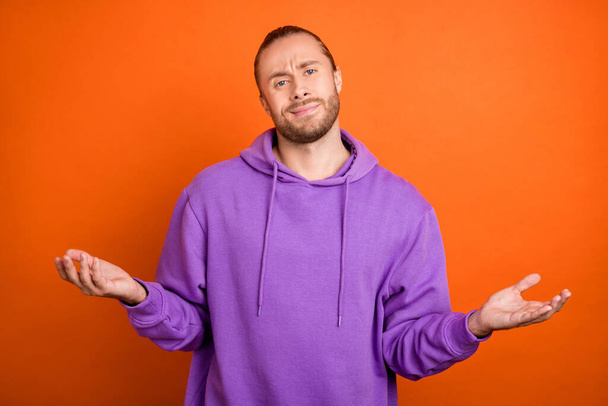 Photo of sad young brown hairdo guy wear violet pullover isolated on orange color background - Foto, Bild
