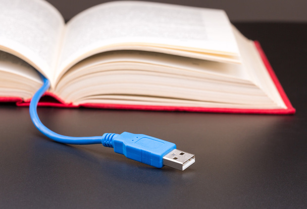 Cable USB sobresale del libro rojo
 - Foto, Imagen