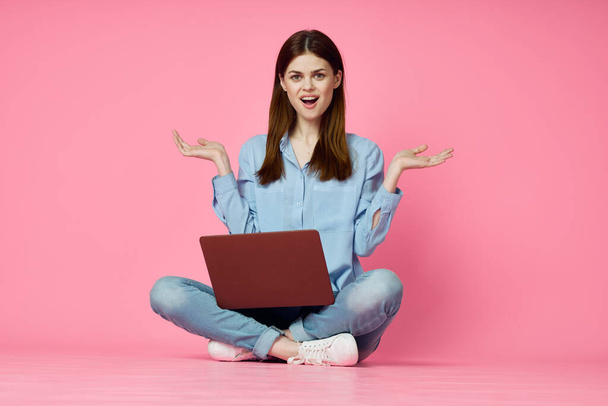 woman with laptop sitting on floor technology internet shopping pink background - Foto, afbeelding