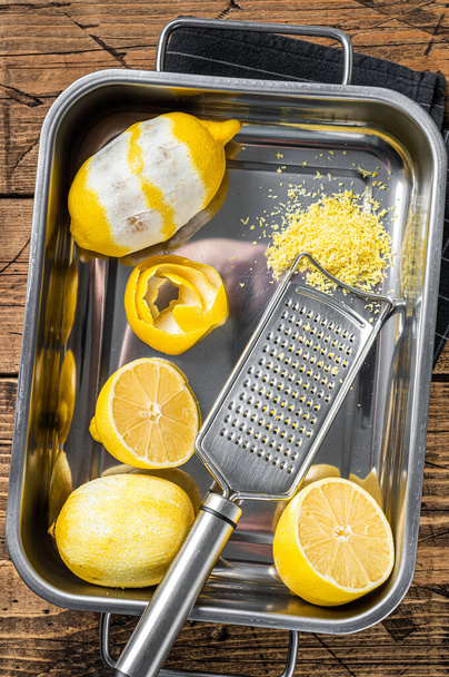 Vaření s nastrouhanou citrónovou kůrou a spirálovou kůrou v kuchyňském podnosu. Dřevěné pozadí. Horní pohled - Fotografie, Obrázek