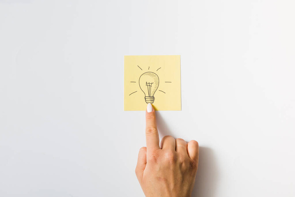 close up person touching finger drawn light bulb sticky note. High quality photo - Фото, зображення