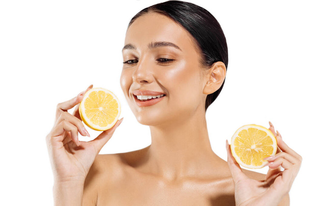The beauty. Woman and fruit portrait. Happy beautiful natural woman holding a juicy orange near her face on a white background, Beautiful girl uses citrus fruits and natural vitamins for healthy skin - Fotoğraf, Görsel