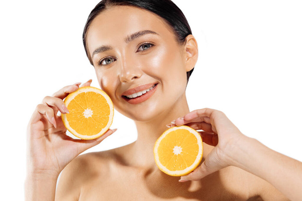 The beauty. Woman and fruit portrait. Happy beautiful natural woman holding a juicy orange near her face on a white background, Beautiful girl uses citrus fruits and natural vitamins for healthy skin - Photo, Image