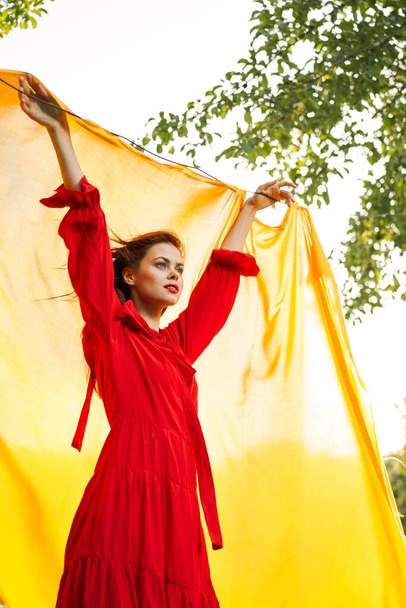 festively outdoors yellow cloth on the background of posing red dress - Zdjęcie, obraz