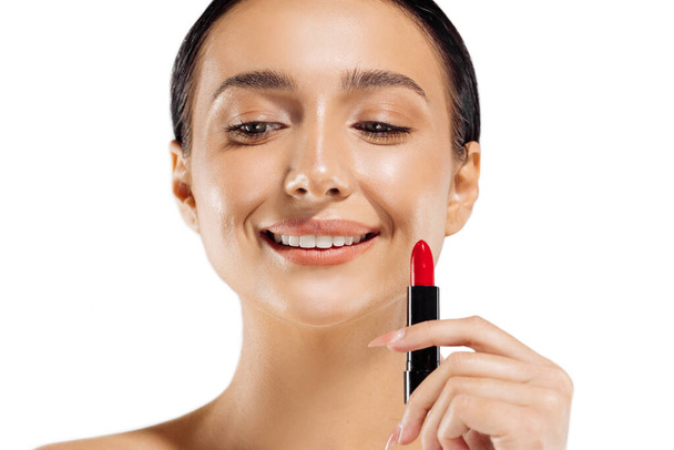 Beautiful young woman with lipstick, photo of a brunette with red lipstick on a white background, woman applying lipstick - Φωτογραφία, εικόνα