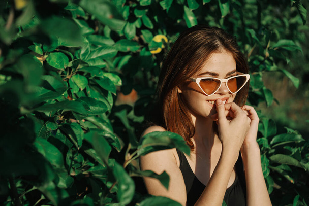 smiling woman wearing sunglasses green leaves nature fashion - Foto, afbeelding