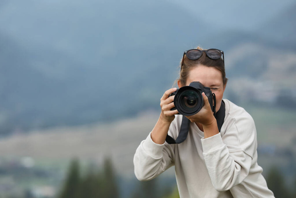 Photographer with modern professional camera in mountains, back view - Foto, Bild