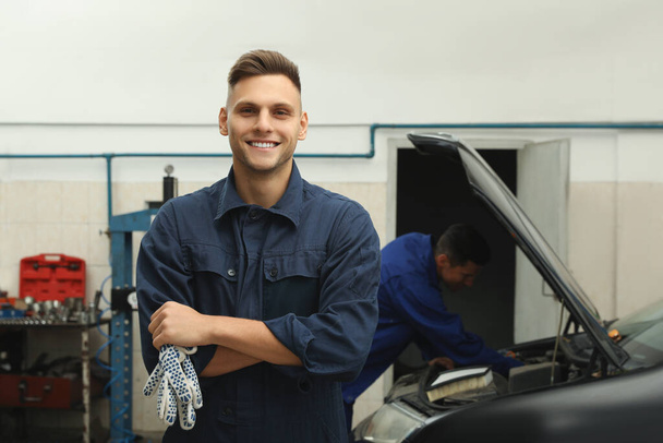 Portrait of professional mechanic at automobile repair shop - Foto, afbeelding