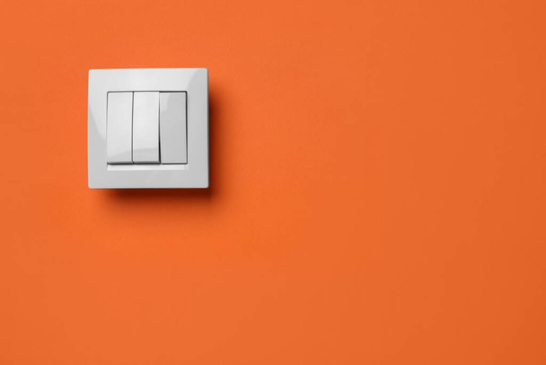 White light switch on orange background. Space for text - Foto, imagen