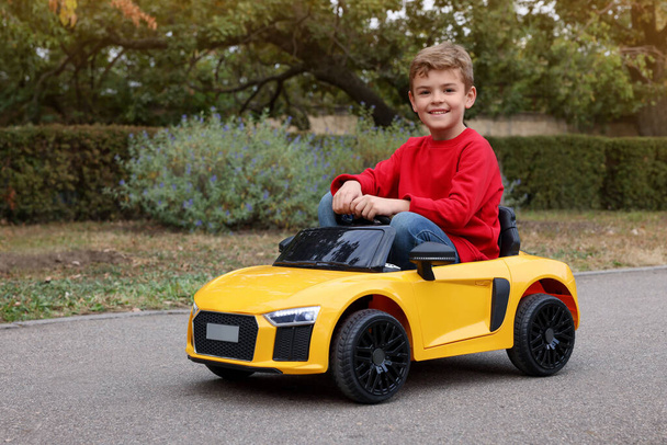 Cute little boy driving children's car outdoors - Foto, immagini