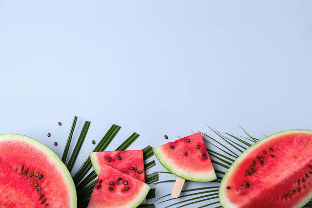 Delicious ripe watermelon and tropical leaves on light background, flat lay. Space for text - Foto, Imagem