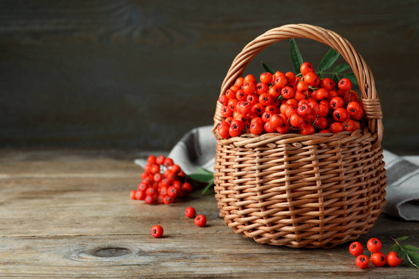 Fresh ripe rowan berries with green leaves on wooden table, space for text - Foto, afbeelding