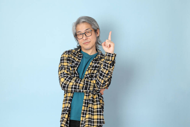 The senior Asian man with yellow plaid shirt standing on the blue background. - Fotoğraf, Görsel