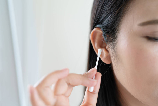 γυναίκα καθαρισμό αυτί με βαμβακερό μάκτρο. Έννοια της υγειονομικής περίθαλψης και του καθαρισμού αυτιών - Φωτογραφία, εικόνα