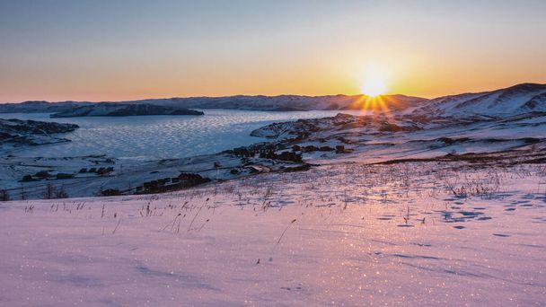 Zimní úsvit na Sibiři. Paprsky vycházejícího slunce osvětlují hory, zamrzlé jezero. Obloha je zvýrazněna oranžově. Sníh jiskří. Ranní zlatá hodina. Bajkal - Fotografie, Obrázek
