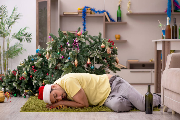 Young man cleaning the apartment after Christmas party - 写真・画像