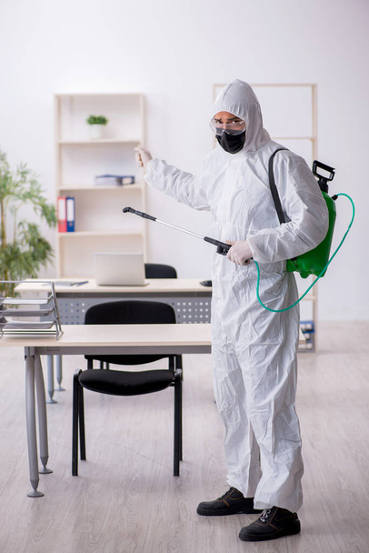 Junger Mann desinfiziert Büro während Pandemie - Foto, Bild