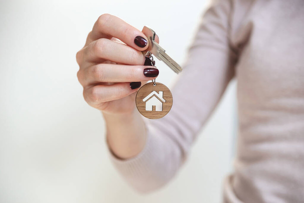 Σχέδιο ακίνητης περιουσίας. Κλειδιά με μπρελόκ σε σχήμα σπιτιού σε γυναικείο χέρι. - Φωτογραφία, εικόνα