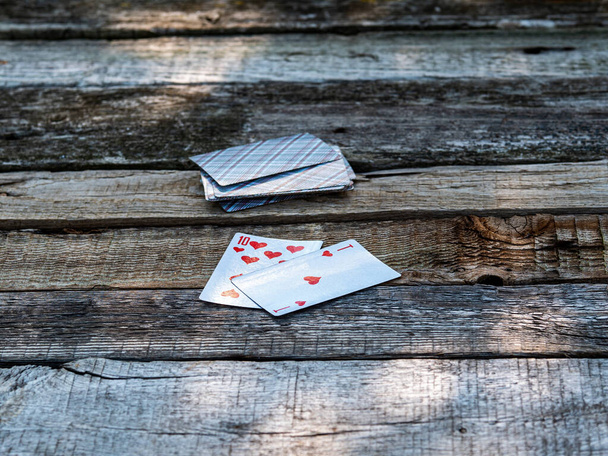 Παίζοντας χαρτιά άσσος και δέκα σε ένα ξύλινο τραπέζι. - Φωτογραφία, εικόνα