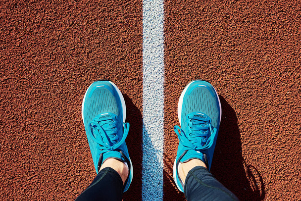 Mannelijke loper voeten met blauwe sneakers stadion track, close-up. Sportschoenen om te joggen. Fitness en gezond lifestyle concept - Foto, afbeelding