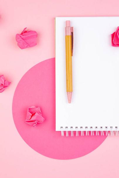 Notepad and pen on a pink background in a flat lay style with a paper crimson circle on the background. Planning concept for 2022. - Фото, изображение