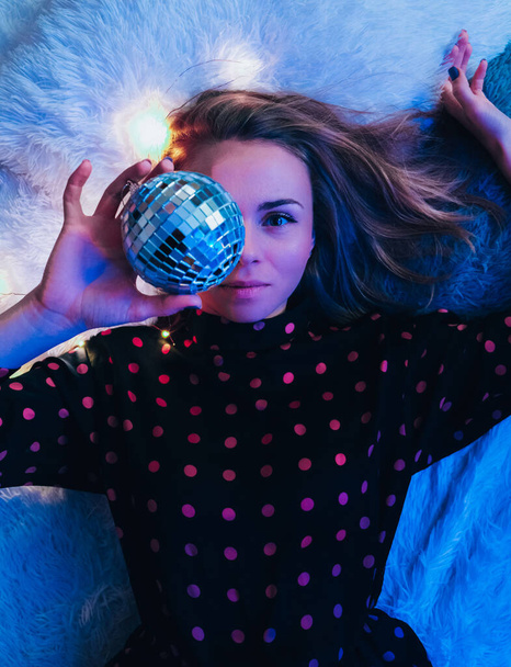 Beautiful young woman lying down with disco ball. Party concept. New year christmas or birthday party. Joyfull happines and magic dreaming. Having fun - Fotografie, Obrázek