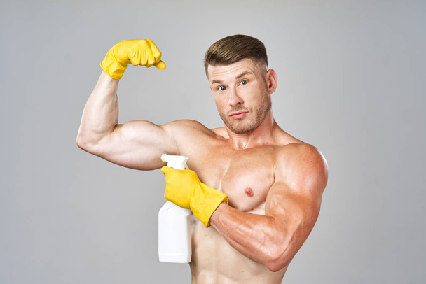 pumped up man posing with detergent in rubber gloves - Фото, изображение
