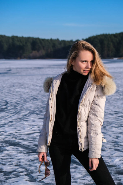 若い女性の笑顔と離れて雪の風景の中に。ヒップホップ暖かい冬の服を着た幸せなヒップスターの女の子。凍った川、湖に滞在。若い魅力的な笑顔の女性の冬の肖像 - 写真・画像