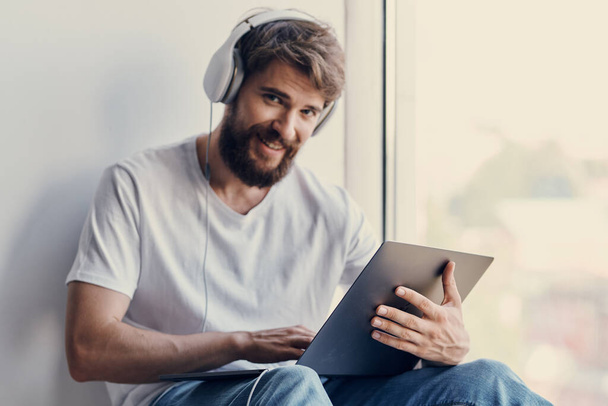 man with headphones sitting on the windowsill technologies - Photo, image