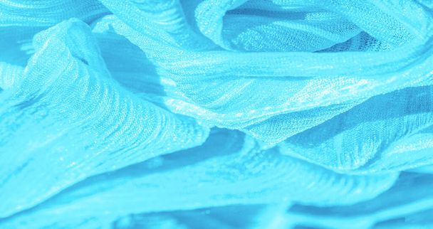 Silk fabric. Texture of blue wrinkled fabric. Blue wrinkled, wavy surface texture. Close-up, soft focus. background, pattern - 写真・画像