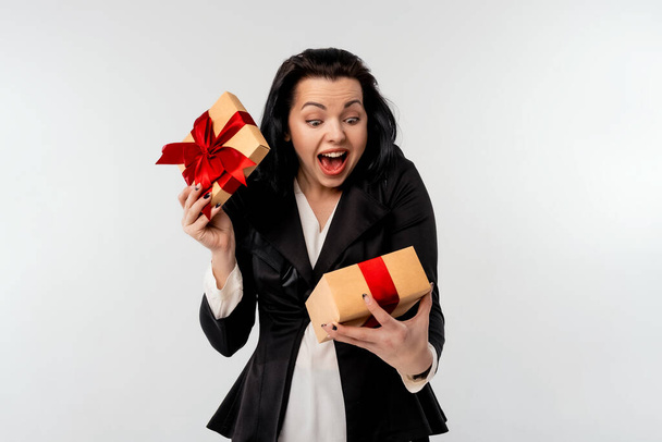 Happy amazed businesswoman in black formal suit jacket opened present over white background. Holidays, celebration and lifestyle concept - Foto, imagen