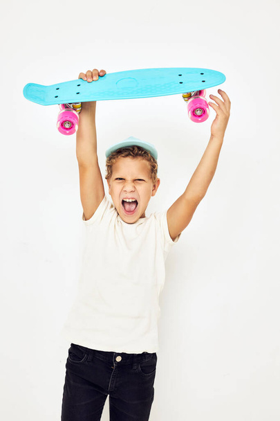 adorable stylish boy in a blue hat with a skateboard light background - Foto, Imagem